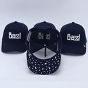 Ein Produktfoto von drei dunkelblauen "Bazi"-Trucker-Kappen, das verschiedene Details zeigt. Während zwei Kappen im Hintergrund die Vorderseite präsentieren, ist die Kappe in der Mitte umgedreht, um die gemusterte Unterseite des Schirms und das Mesh-Innere zu zeigen.
