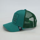 Eine grüne Trucker-Kappe mit "Bulldog"-Aufnäher, fotografiert in der Seitenansicht vor einem weißen Hintergrund. Diese Ansicht zeigt deutlich den Ton-in-Ton gestickten Aufnäher auf der Vorderseite und den passenden grünen Mesh-Einsatz am Hinterkopf.