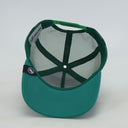 Ein Produktfoto, das die Innenansicht einer grünen Trucker-Kappe auf einem weißen Hintergrund zeigt. Der Fokus liegt auf der inneren Konstruktion, dem atmungsaktiven Mesh-Gewebe und dem verstellbaren, hellgrünen Snapback-Verschluss am hinteren Teil.