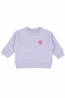 Die Vorderansicht eines schlichten, hellvioletten Babysweaters mit einem kleinen pinken Smiley-Badge auf der Brust.