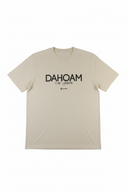 Frontalansicht eines flach liegenden, beigefarbenen Unisex-T-Shirts auf weißem Grund. Mittig auf der Brust ist der schwarze Schriftzug „DAHOAM is am scheensten“ sowie ein kleines Markenlogo darunter zu sehen.