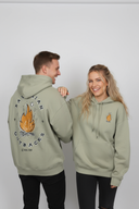 Ein Paar, ein Mann und eine Frau, posieren fröhlich in identischen, salbeigrünen Kapuzenpullovern. Der Mann, der zur Seite lacht, zeigt den großen "Bavarian Outback"-Rückenaufdruck, während die Frau, die strahlend in die Kamera blickt, die Vorderseite mit einem kleinen Logo präsentiert und ihre Hand auf seine Schulter legt.