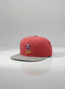 Ein professionelles Produktfoto einer pinken Kappe mit grauem, flachem Schirm. Auf der Vorderseite befindet sich das bunte, gestickte "Oimi"-Logo. Die Kappe steht auf einer spiegelnden Oberfläche vor einem hellen Studiohintergrund und erzeugt eine deutliche Reflexion.