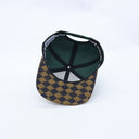 Die Innenansicht der grün-braunen "Rewe Hoamat"-Kappe. Das Foto zeigt die grüne Innenkonstruktion und den Snapback-Verschluss, mit besonderem Fokus auf die Unterseite des Schirms, die ein markantes braun-schwarzes Rautenmuster aufweist.